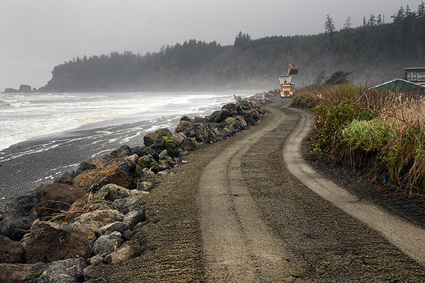 Construction of a sea wall made of large rocks with a sandy road on top