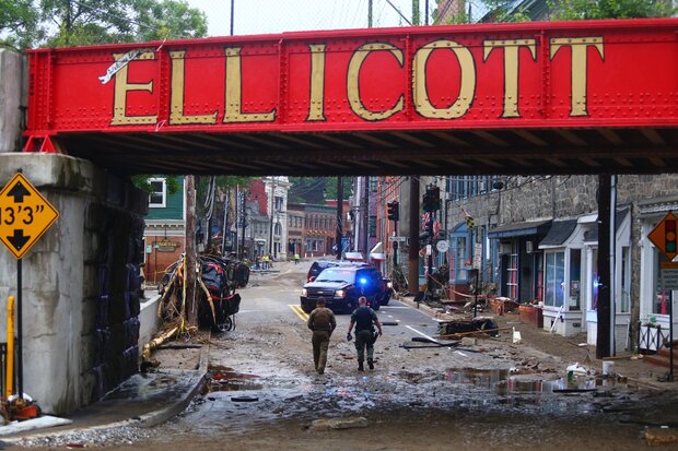 Overhead sign reads Ellicott, storm damage on road